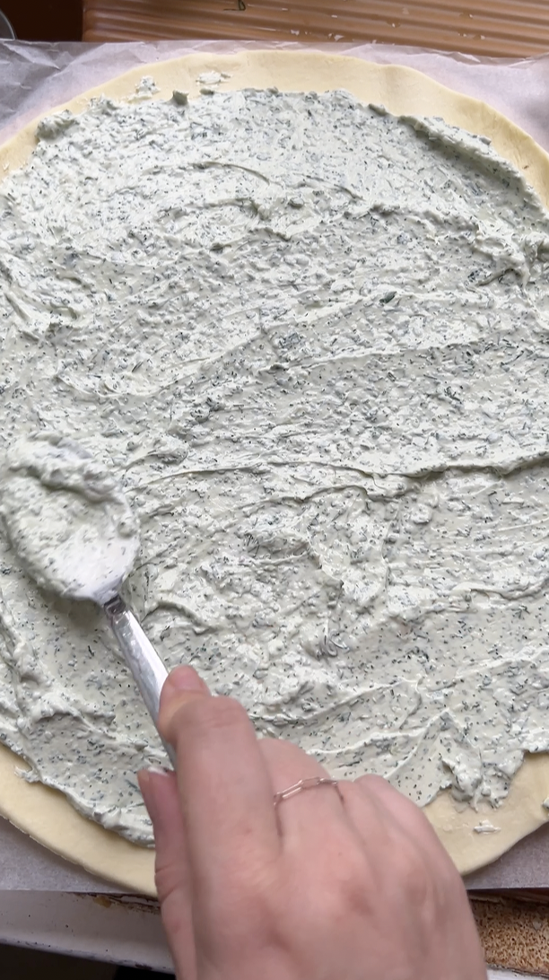 Herbed ricotta cream spread on pie crust before baking.