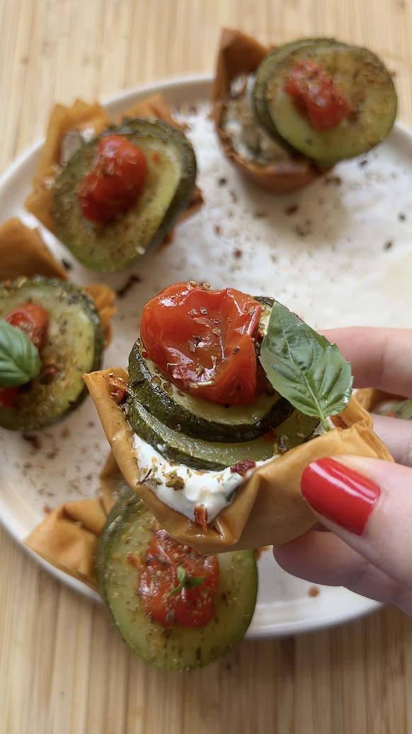 Confit vegetables and basil leaves are added on top of the cream cheese, in the small golden baked cup.