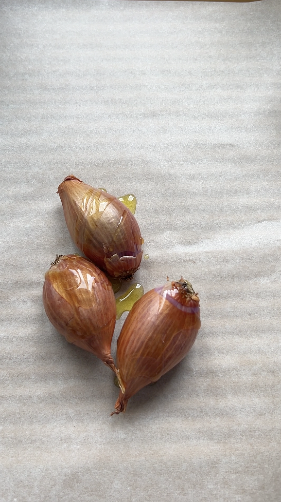 Shallots on parchment paper, with olive oil and oregano.