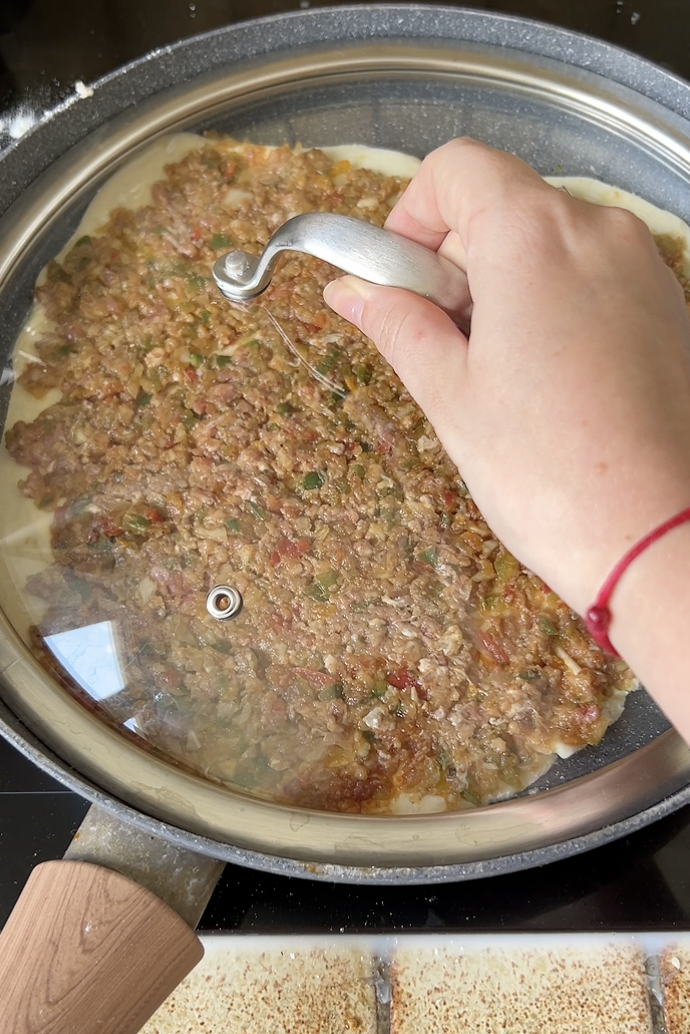 Lahmacun cooking in a pan with a lid.