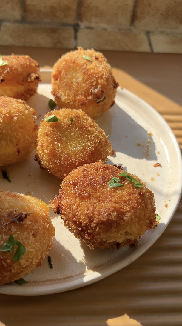 Plusieurs Mac and cheese balls dans une assiette beige.