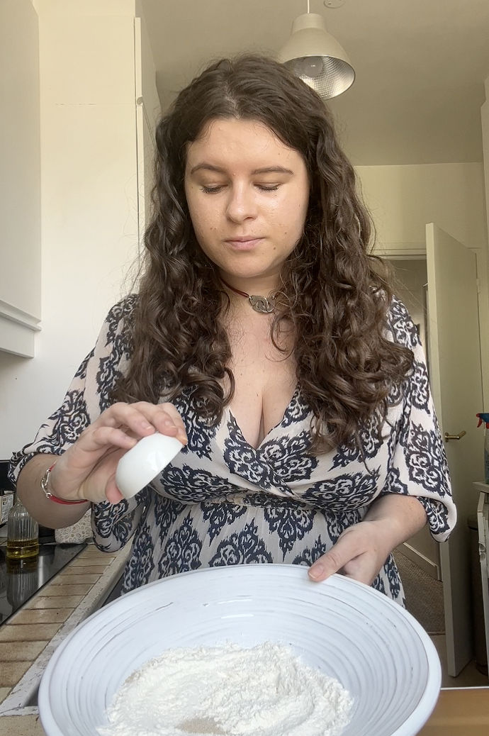 Marie adding the yeast to the large bowl of flour.