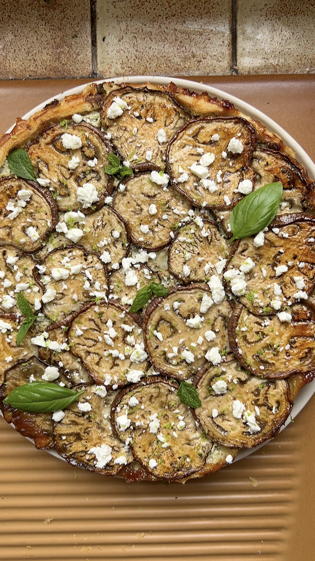 Tarte tatin d'aubergines après la cuisson, avec de la feta, des zestes de citron vert et des herbes fraîches.