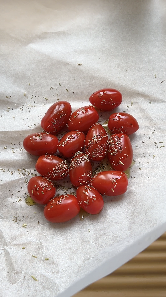 Tomates cerises posées sur du papier cuisson, avec de l'huile d'olive et de l'origan.