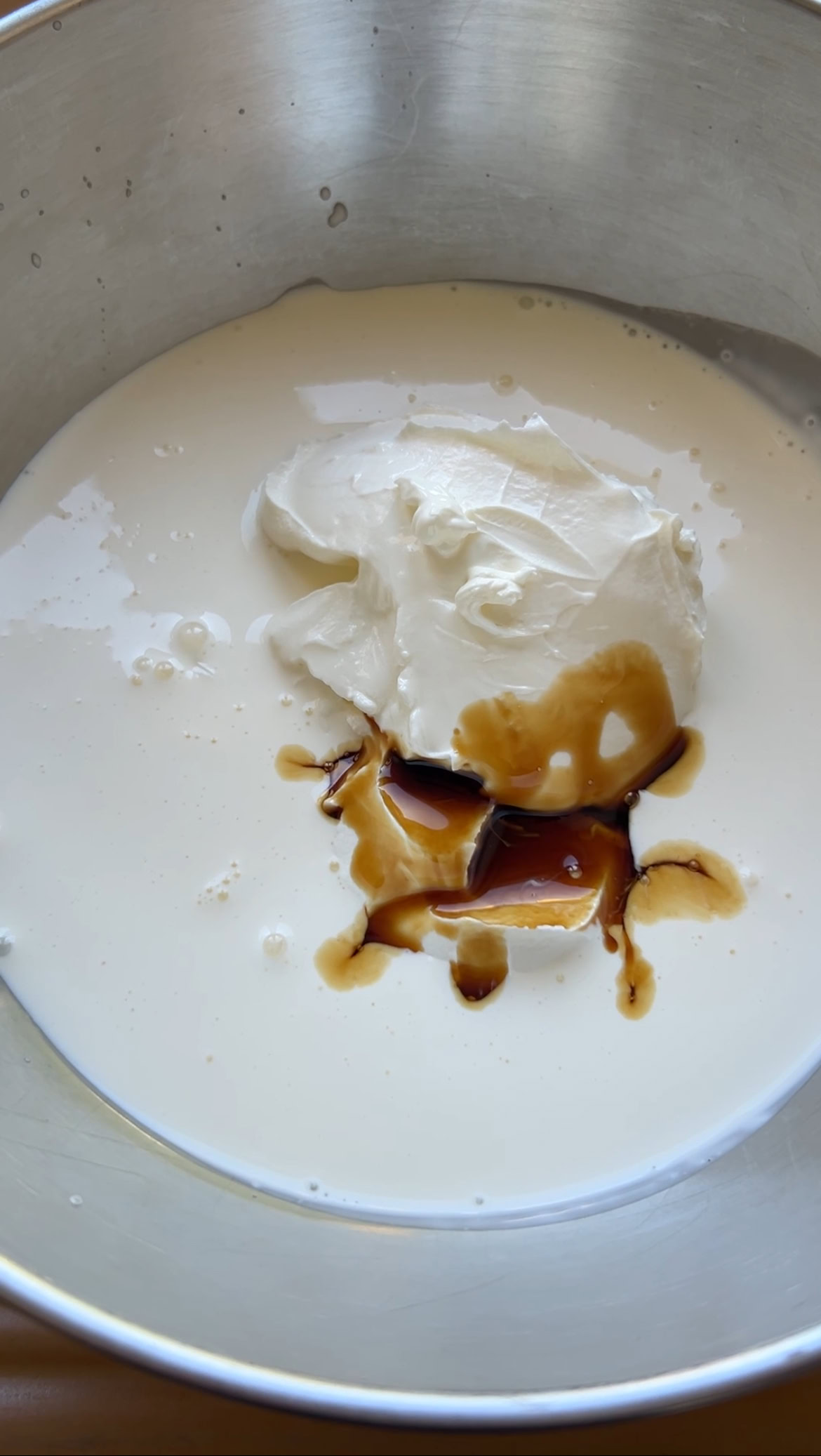 Crème liquide, mascarpone et extrait de vanille dans un bol en inox.