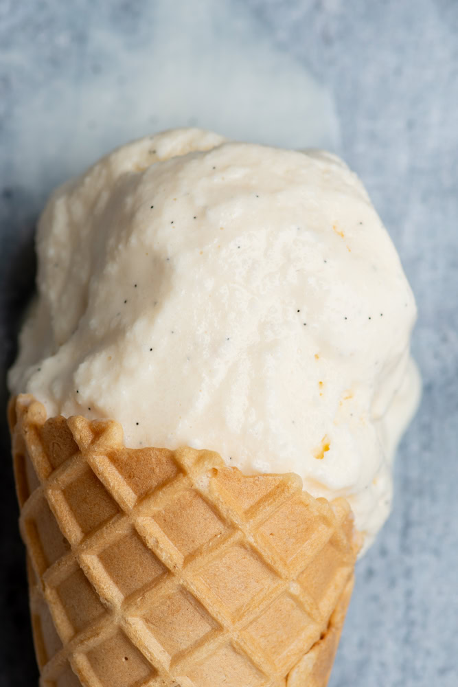 Scoop of homemade vanilla ice cream in a cone.