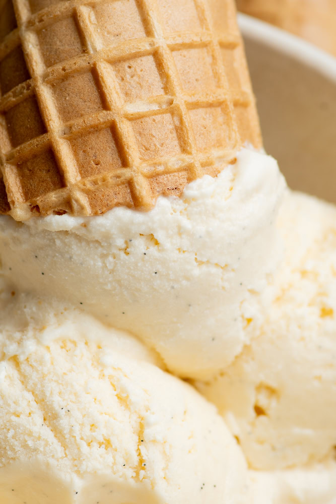 Boules de glace vanille maison dans un bol avec un cornet sur l'une d'entre elles.