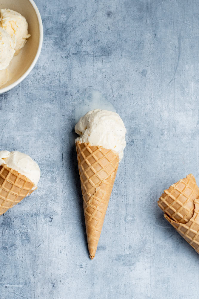 Boules de glace vanille dans deux cornets et dans un bol. Deux autres cornets en bas à droite.