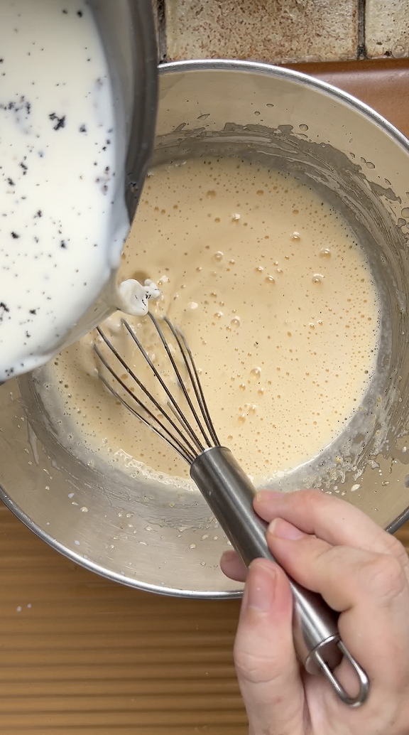 Casserole de lait versée petit à petit sur le mélange de jaunes d'oeuf et de sucre battu.