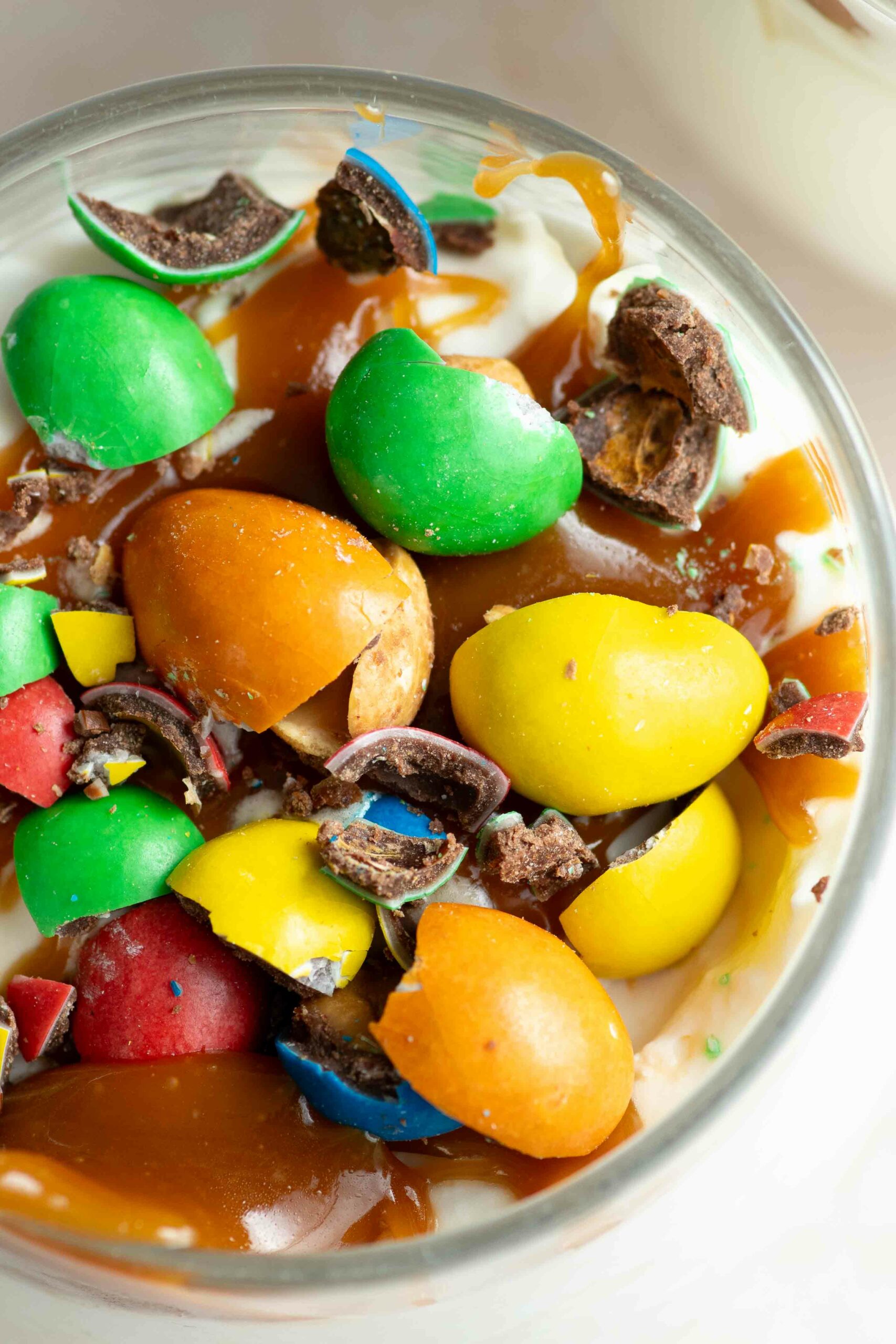 Homemade McFlurry in a glass, with caramel topping and crushed M&Ms on top.