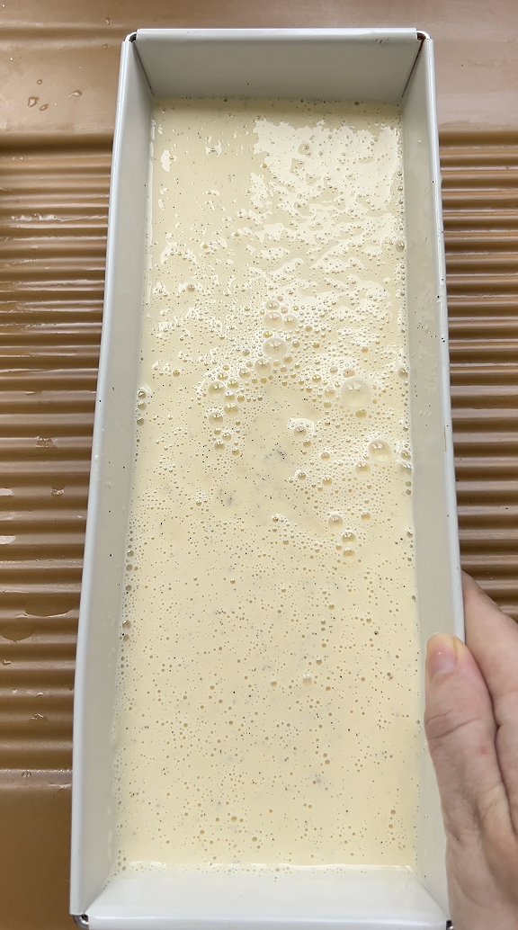 Crème anglaise versée dans un moule rectangulaire.