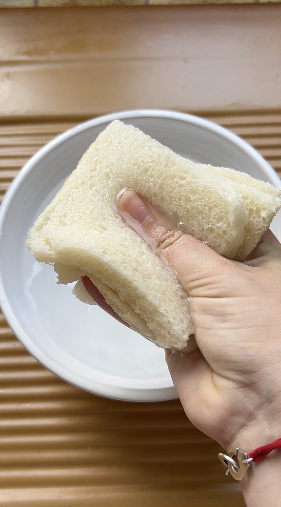 Une main qui essore les tranches de pain de mie.