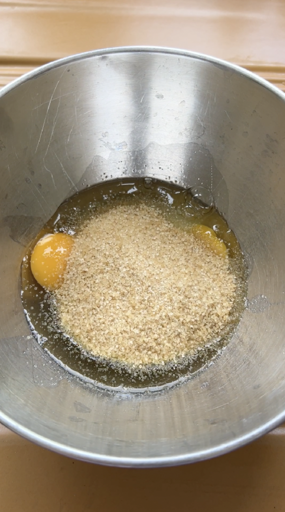 Brown sugar and eggs in a stainless steel bowl.