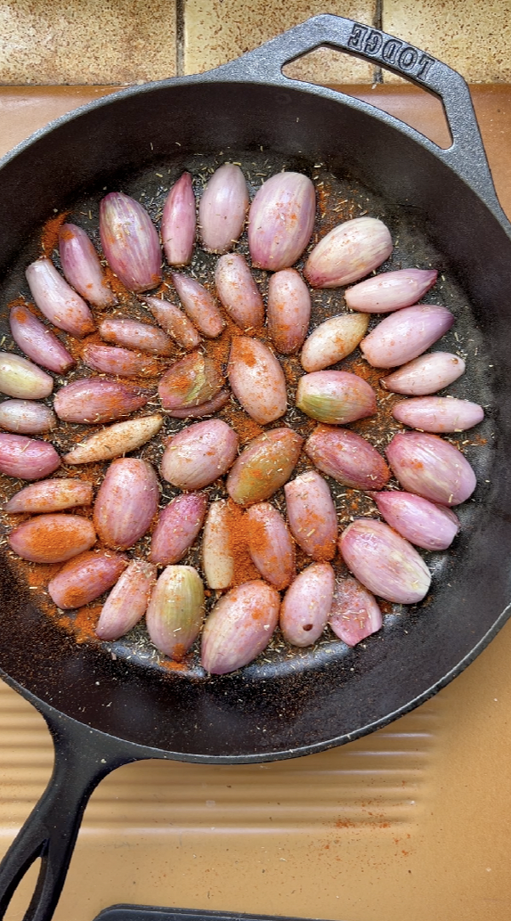 Paprika et herbes de Provence rajoutés sur les échalotes, dans la poêle noire.