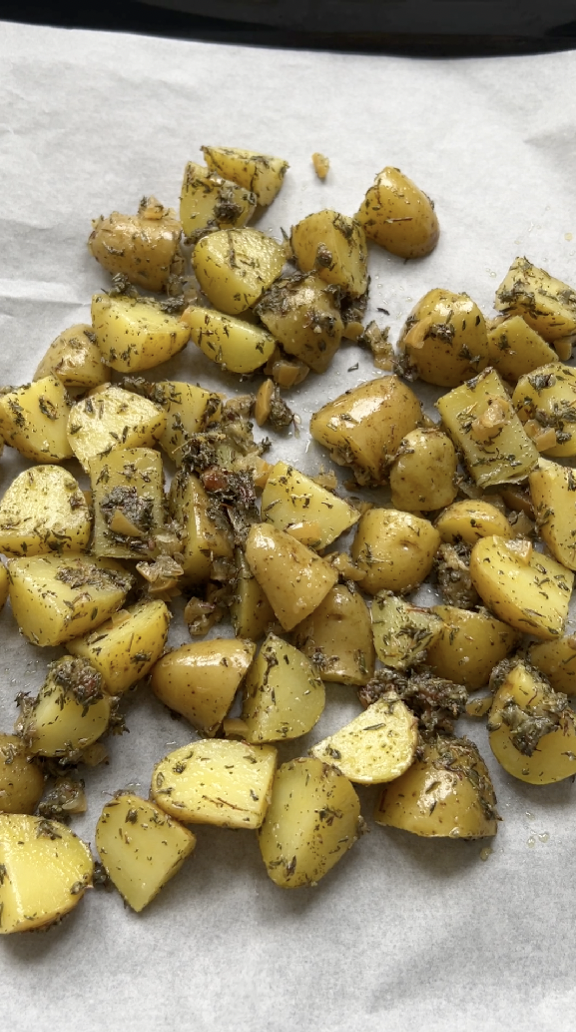 Seasoned potatoes on a baking tray lined with parchment paper.