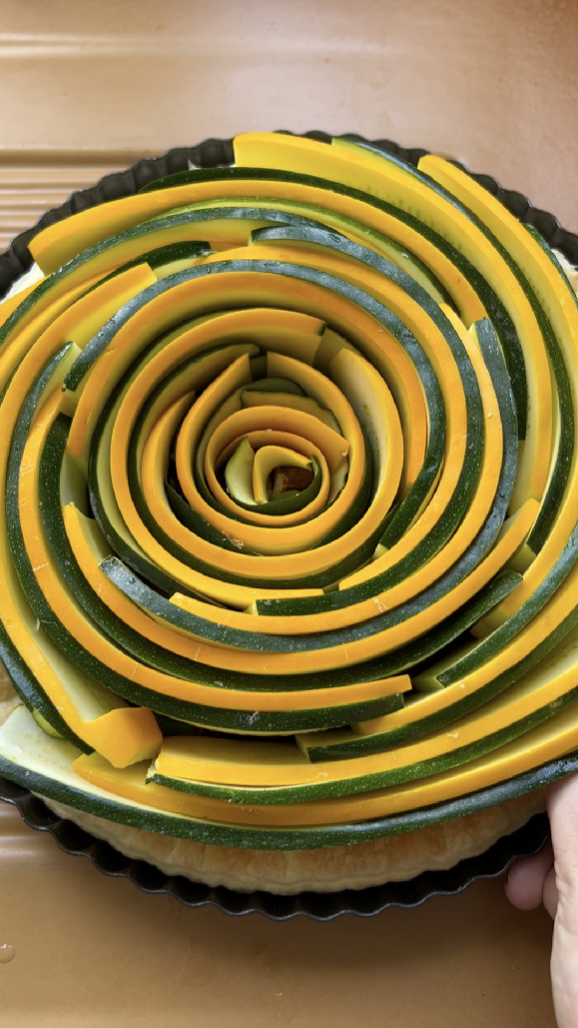 Spiral-shaped slices of green and yellow zucchini on puff pastry.