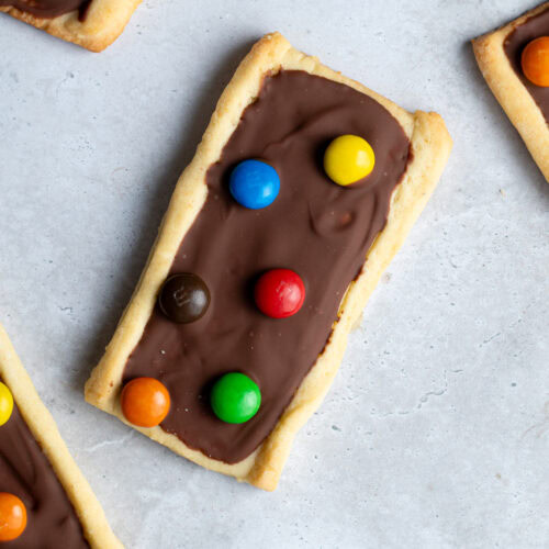 Several chocolate M&Ms shortbread biscuits on a gray work surface.