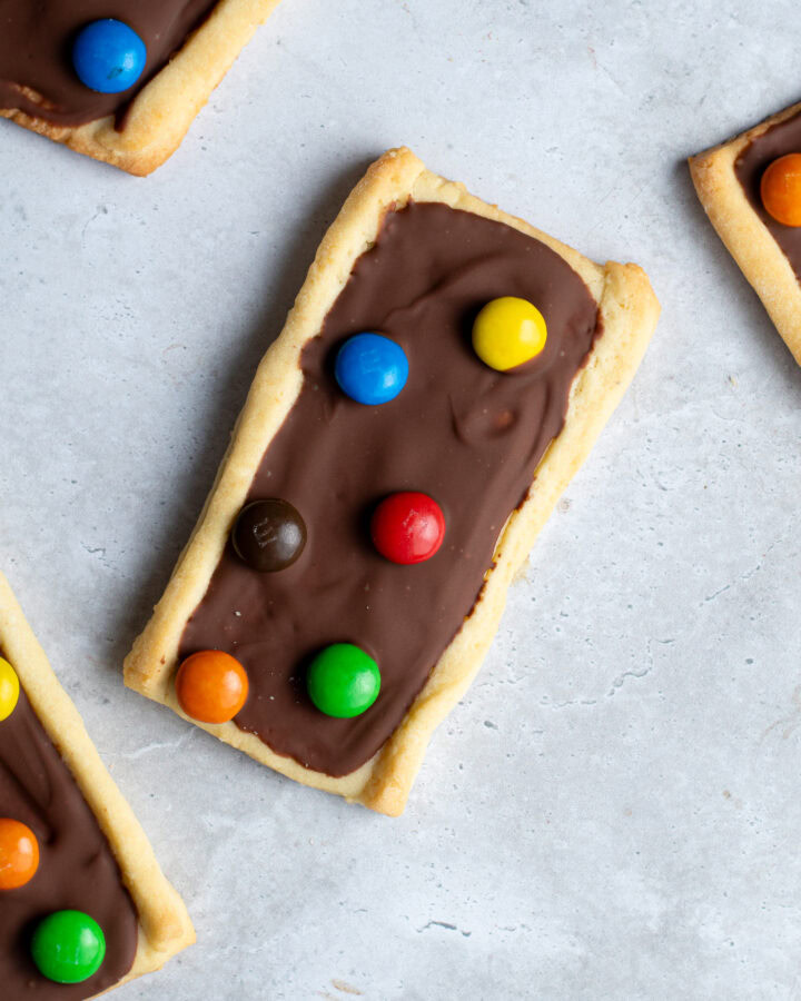 Several chocolate M&Ms shortbread biscuits on a gray work surface.