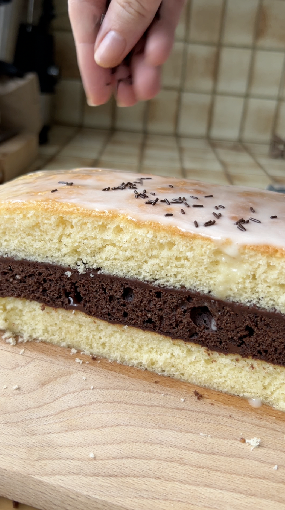 Une main qui parsème le Napolitain de vermicelles en chocolat.