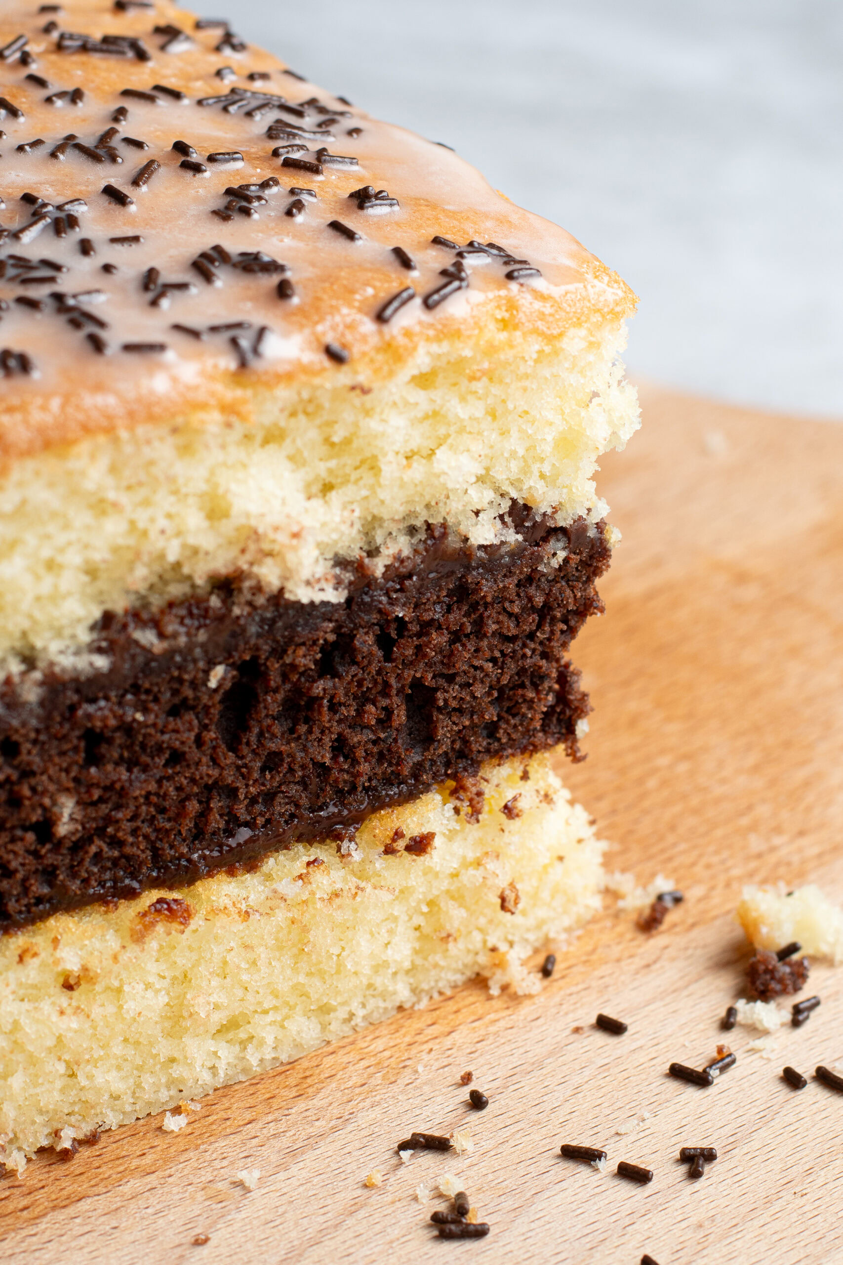 Soft, homemade French layered chocolate and vanilla sponge cake on a wooden board.