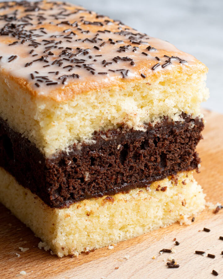 Soft, homemade French layered chocolate and vanilla sponge cake on a wooden board.