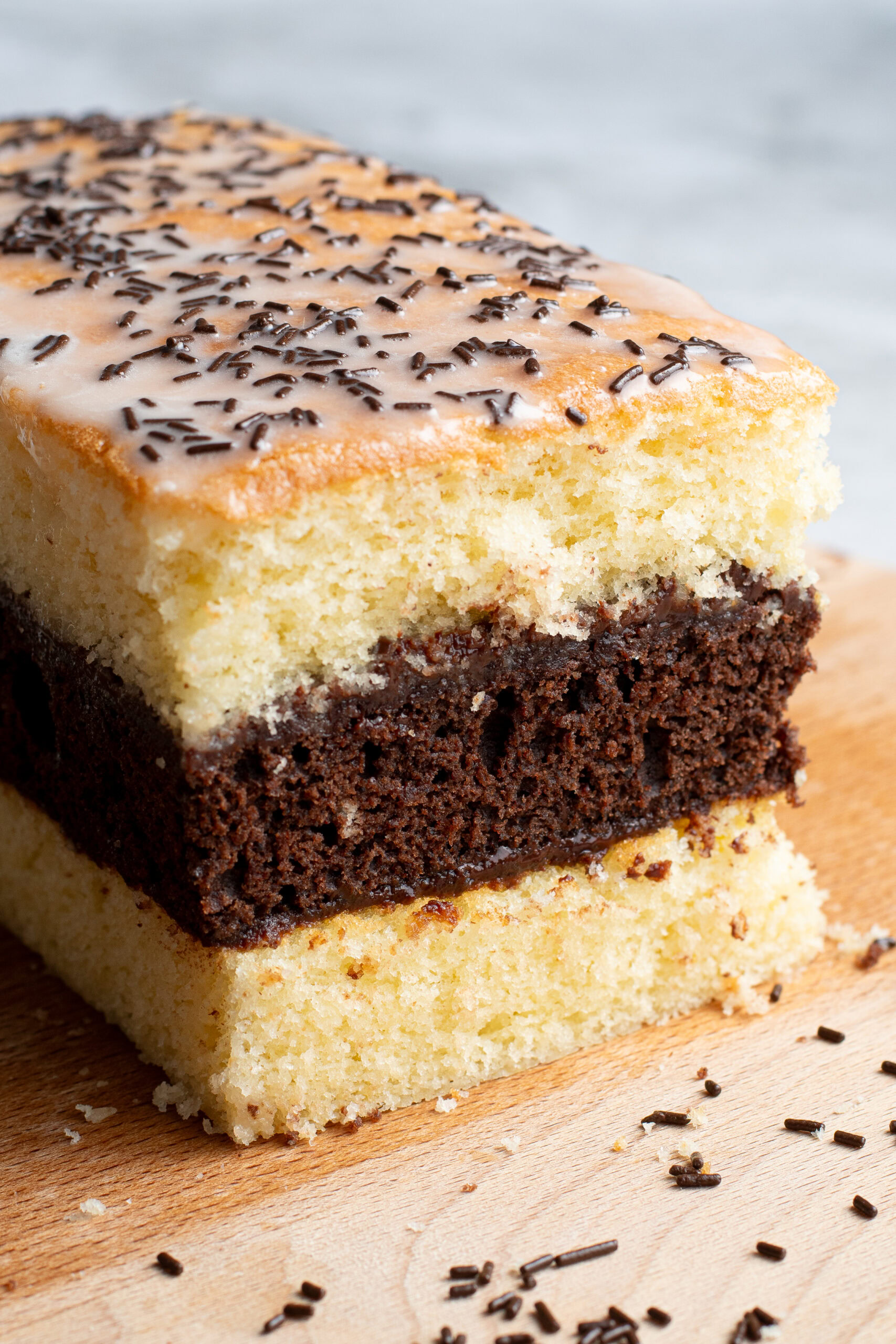 Soft, homemade French layered chocolate and vanilla sponge cake on a wooden board.