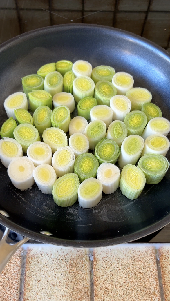 Leek sections cooking in a pan.