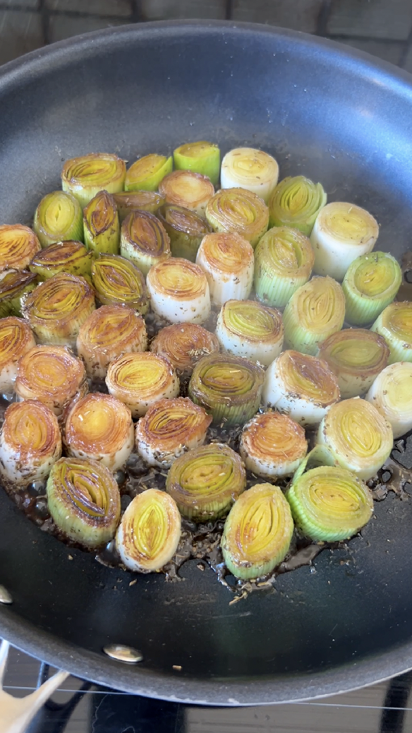 Leek sections cooking in a pan.