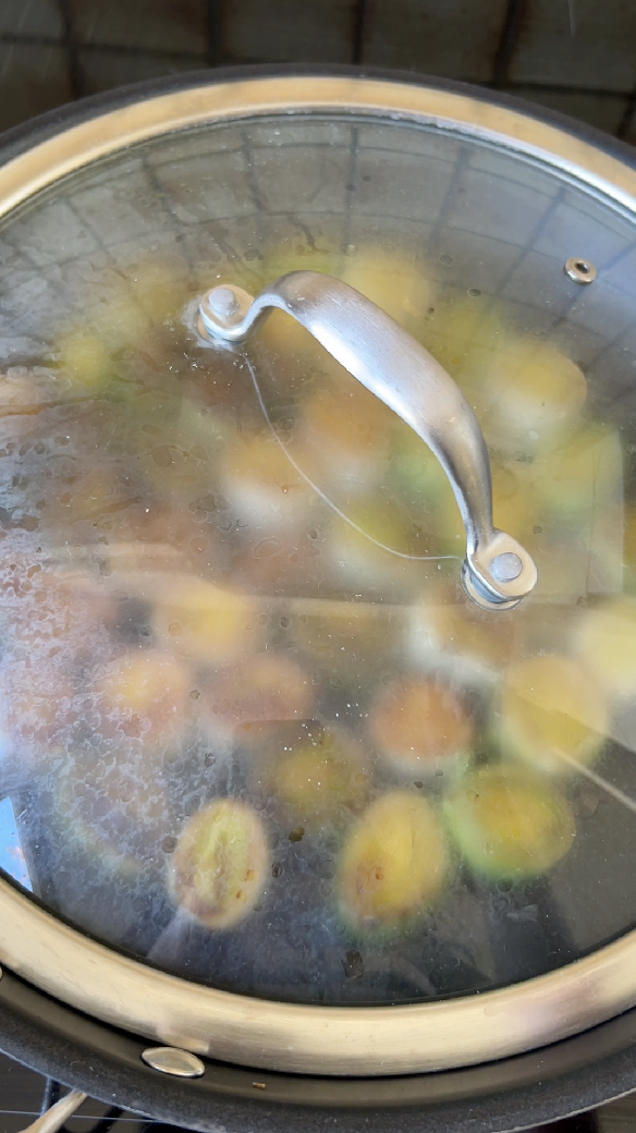 Leek sections cooking in a covered pan.