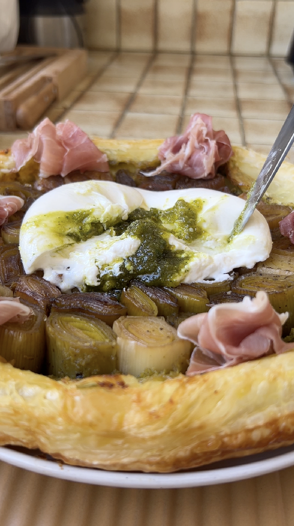 French tart Tatin after baking, topped with burrata stuffed with pistachio pesto and slices of Parma ham.