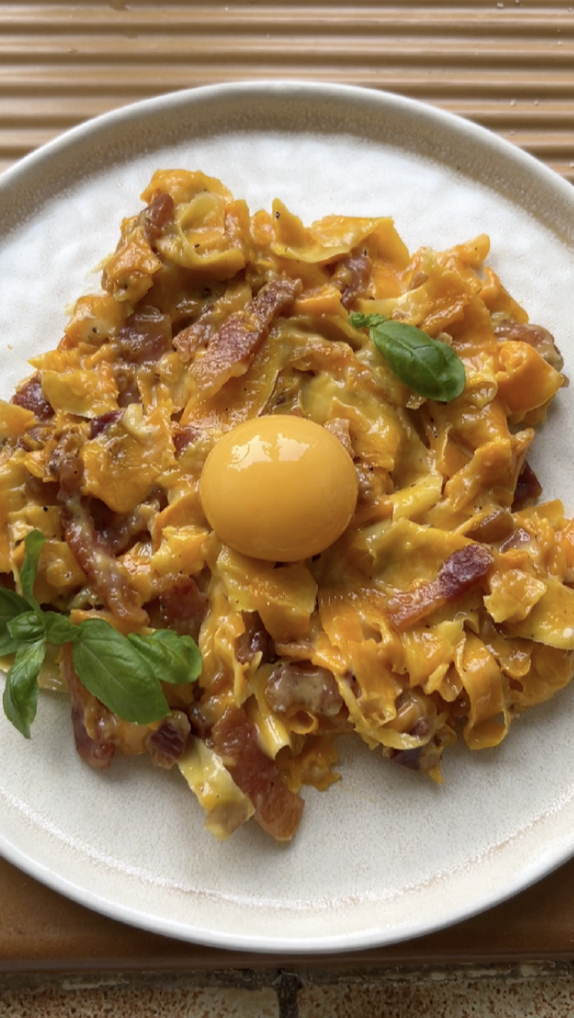 Tagliatelle de courge Carbonara dans une assiette beige.