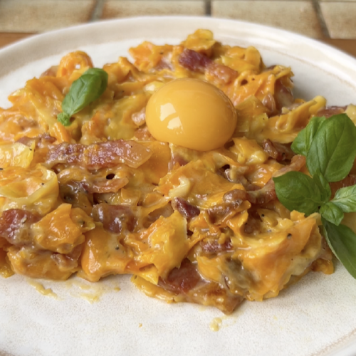 Tagliatelle de courge Carbonara dans une assiette beige.