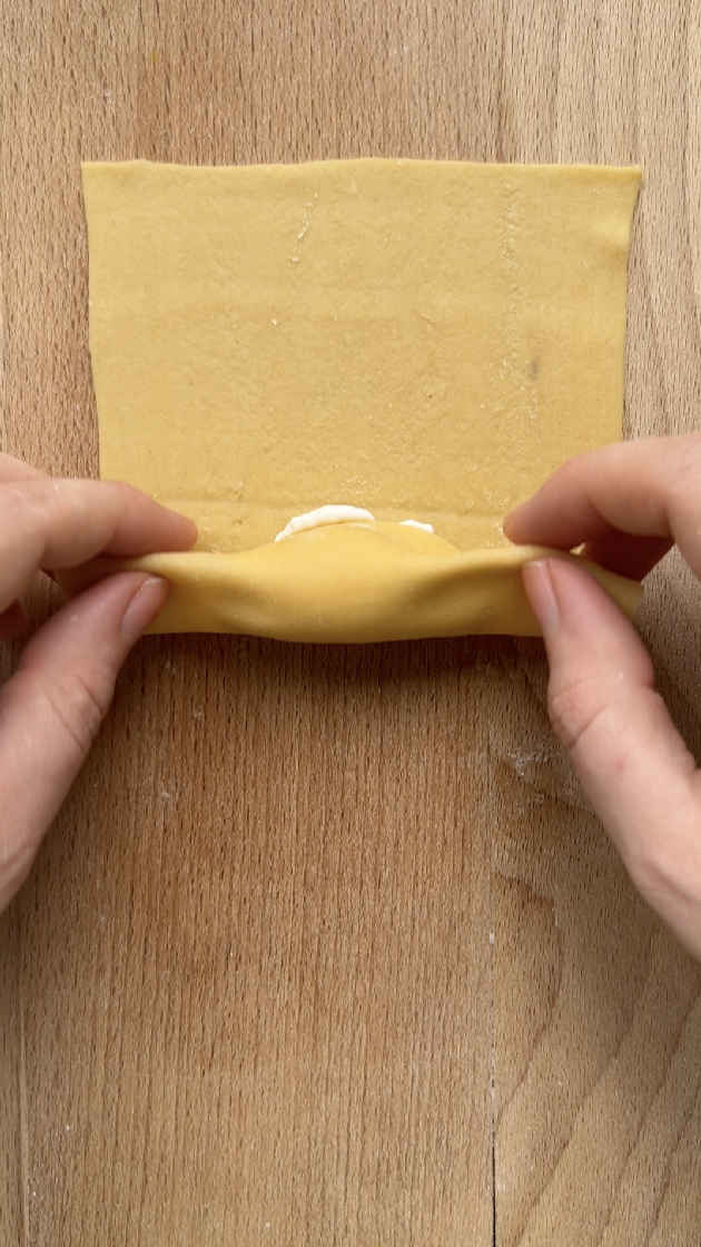 Deux mains qui roulent la feuille de lasagne sur elle-même.