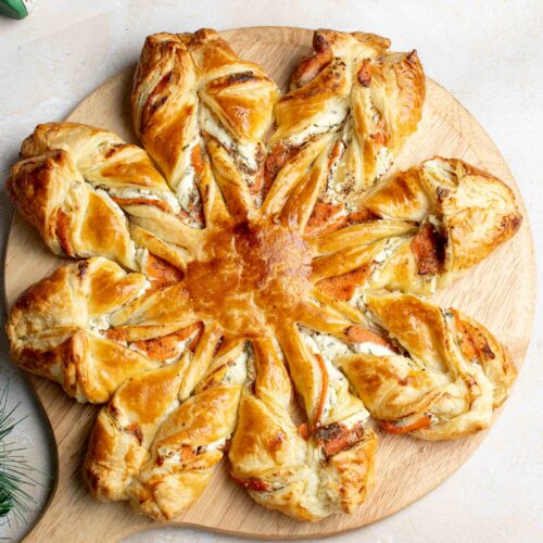 Flocon de Noël feuilleté sur une planche en bois avec une boule de Noël.