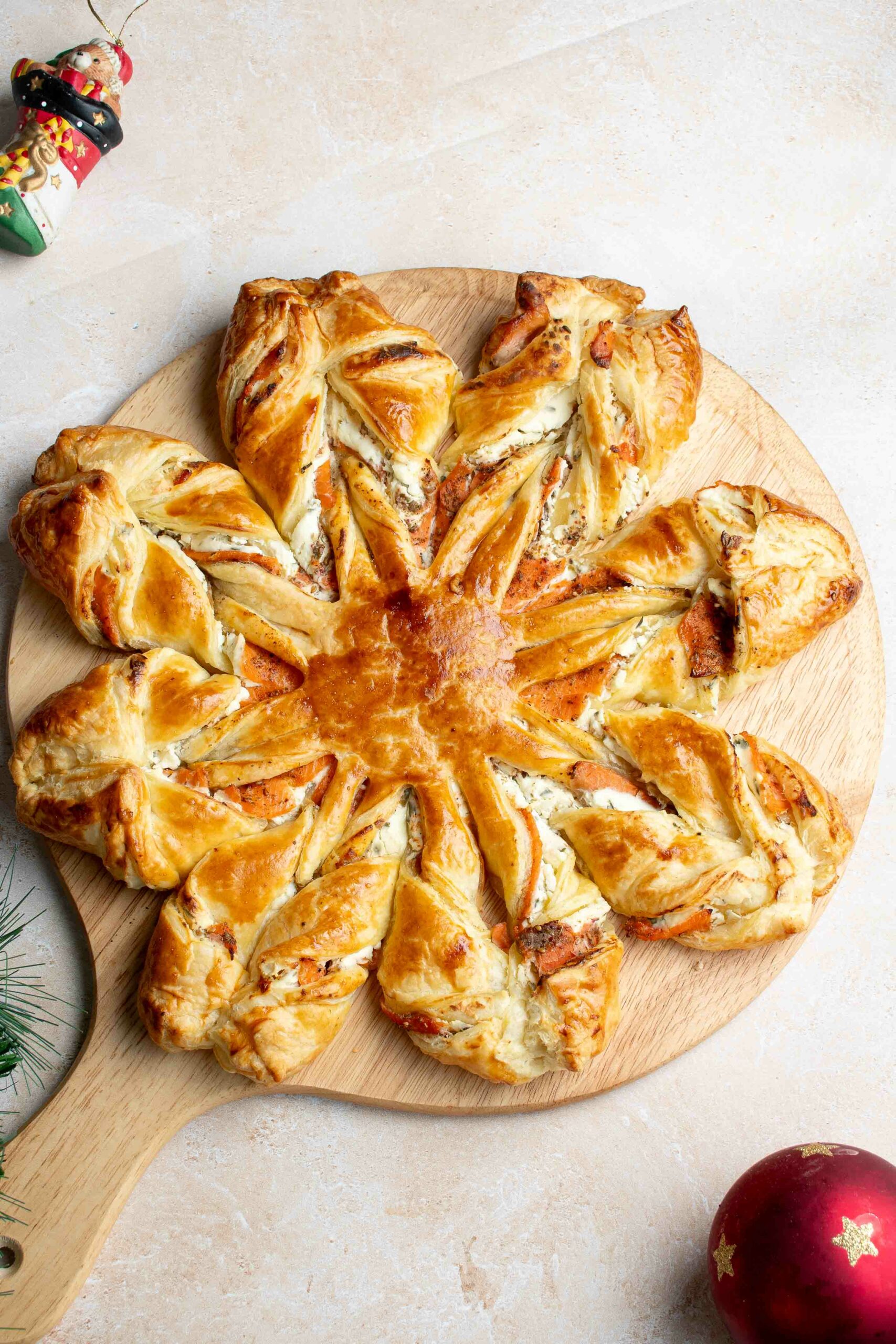 Flocon de Noël feuilleté sur une planche en bois avec une boule de Noël.