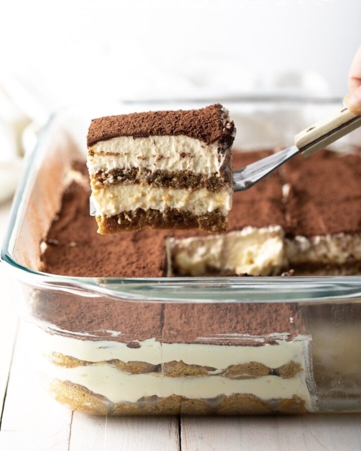 Une spatule qui sort une part de tiramisu du plat.