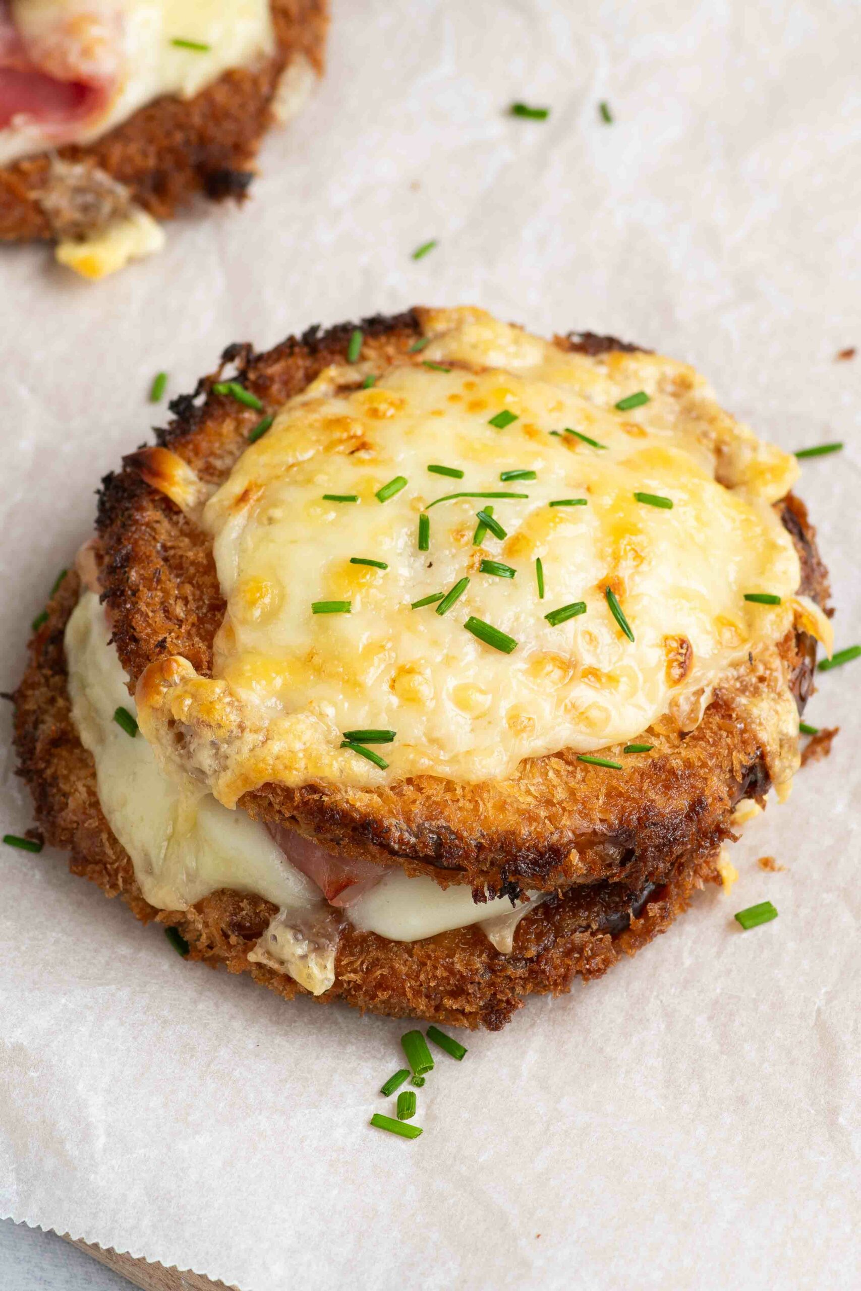 Deux butternut croque monsieur sur une planche en bois recouverte de papier cuisson, avec de la ciboulette.