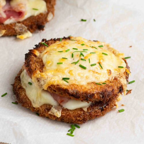 Deux butternut croque monsieur sur une planche en bois recouverte de papier cuisson, avec de la ciboulette.