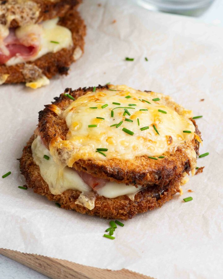 Deux butternut croque monsieur sur une planche en bois recouverte de papier cuisson, avec de la ciboulette.