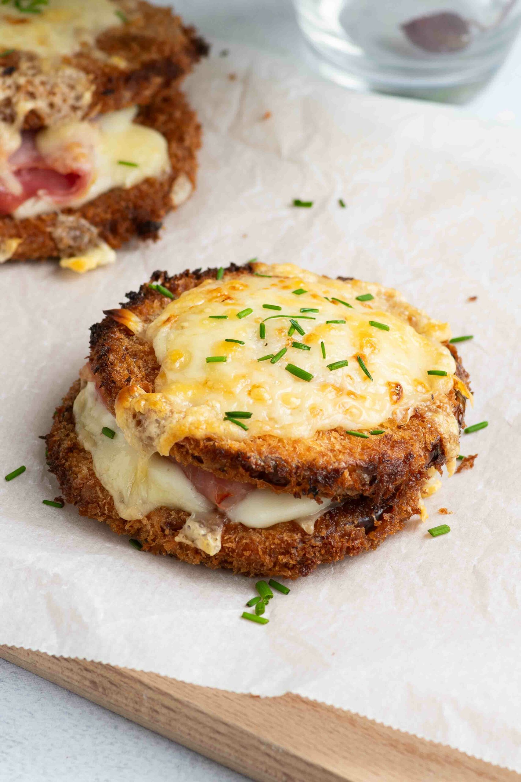 Deux butternut croque monsieur sur une planche en bois recouverte de papier cuisson, avec de la ciboulette.