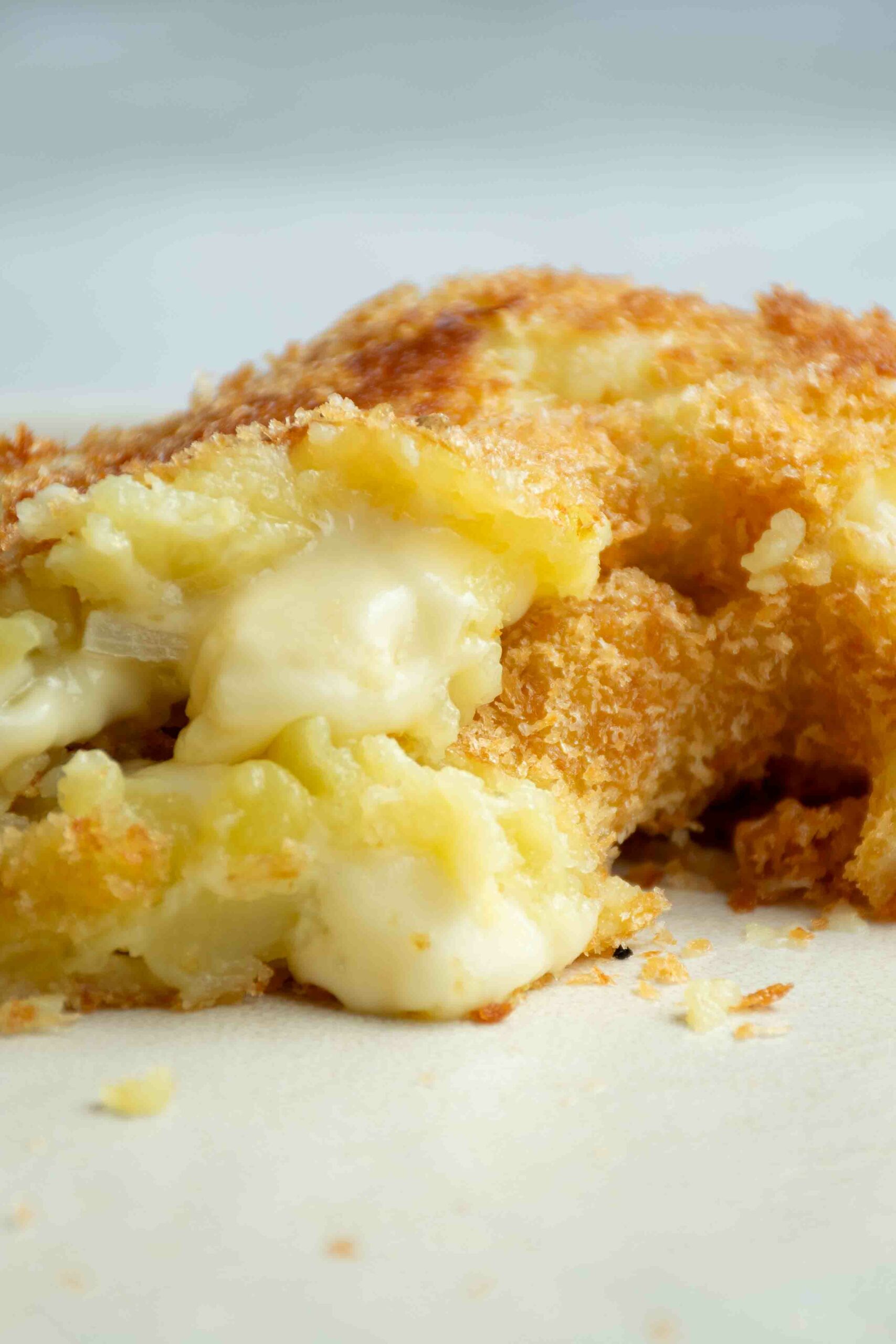 Donuts de pomme de terre coupé en deux avec du fromage qui dégouline.