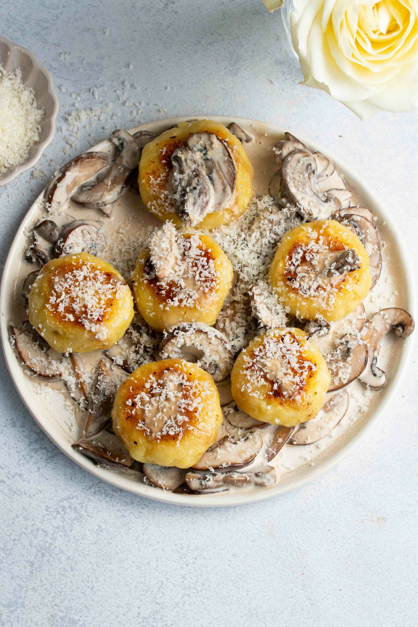 Gnocchi maison farcis de burrata dans une assiette beige avec une sauce crémeuse aux champignons.