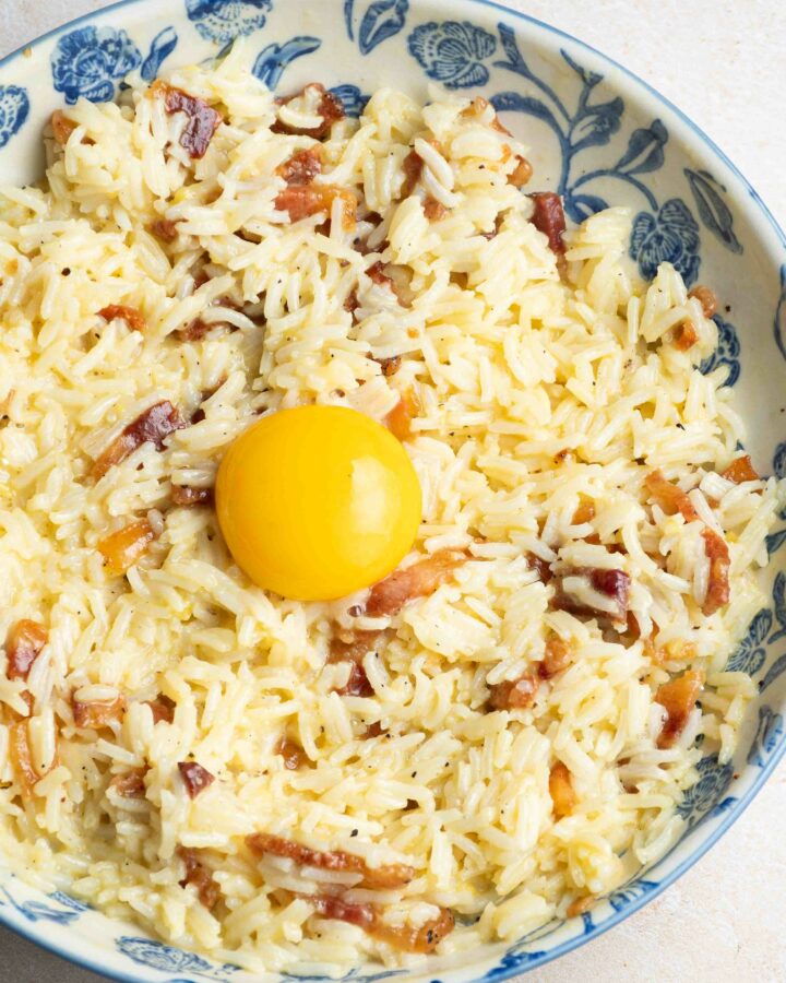 Riz Carbonara avec un jaune d'oeuf, dans une assiette beige et bleue.